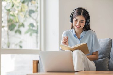 Asyalı kız öğrenci çevrimiçi öğrenme dersi alıyor. Çevrimiçi video öğretmeni, Mutlu Asyalı kız evde bilgisayar laptopuyla İngilizce öğreniyor.