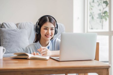 Asyalı kız öğrenci çevrimiçi öğrenme dersi alıyor. Çevrimiçi video öğretmeni, Mutlu Asyalı kız evde bilgisayar laptopuyla İngilizce öğreniyor.