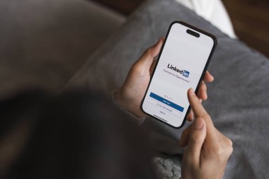 CHIANGMAI, THAILAND - 17 APR 2023: Bir kadın ekranda LinkedIn uygulaması ile Apple iPhone 14 tutuyor. LinkedIn akıllı telefonlar için fotoğraf paylaşım uygulaması...
