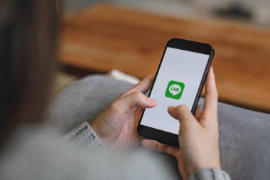 CHIANG MAI, THAILAND - 17 Nisan 2023: Ekranda Apple iPhone 14 'ü tutan kadın. LINE ücretsiz sesli arama yapmanızı ve ücretsiz mesaj göndermenizi sağlayan yeni bir iletişim uygulaması..