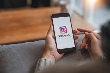 CHIANG MAI, THAILAND - 17 APR 2023: Kafedeki ekranda Apple iPhone 14 uygulaması olan bir kadın var. Instagram akıllı telefonlar için fotoğraf paylaşım uygulamasıdır...