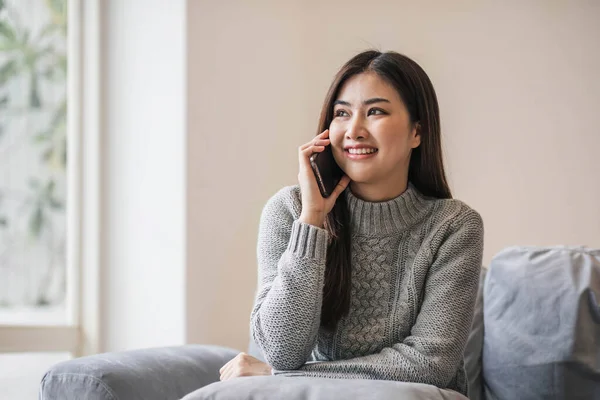 stock image Happy casual beautiful woman is talking on a phone sitting on a sofa at home...