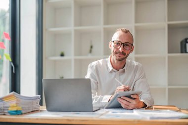 Businessman using laptop computer in office. Happy middle aged man, entrepreneur, small business owner working online...
