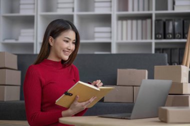 Küçük işletme girişimcisi KME, kutuda kumaş paketleyen Asyalı kadın. Portre genç Asyalı küçük işletme sahibi ev sahibi, çevrimiçi satış pazarlama teslimatı, KME e-ticaret tele pazarlama kavramı