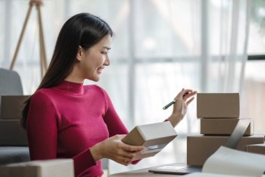 Startup small business entrepreneur SME, asian woman packing cloth in box. Portrait young Asian small business owner home office, online sell marketing delivery, SME e-commerce telemarketing concept