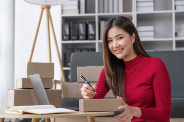 Küçük işletme girişimcisi KME, kutuda kumaş paketleyen Asyalı kadın. Portre genç Asyalı küçük işletme sahibi ev sahibi, çevrimiçi satış pazarlama teslimatı, KME e-ticaret tele pazarlama kavramı