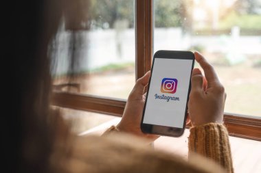 CHIANG MAI, THAILAND - 1 Mayıs 2023: Kafedeki ekranda Apple iPhone 14 uygulaması olan bir kadın var. Instagram akıllı telefonlar için fotoğraf paylaşım uygulamasıdır