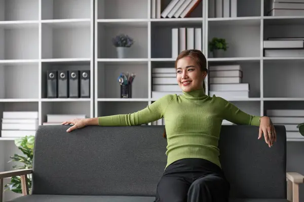 stock image Attractive young Asian woman sits in the minimal and comfortable living room enjoying reading a book...