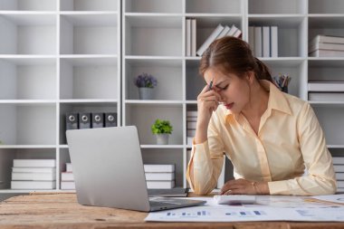 Stresli genç Asyalı iş kadını masasındaki mali yatırım raporlarını yeniden kontrol etmeye odaklanıyor...