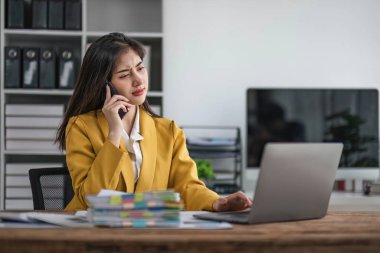 Genç meşgul Asyalı iş kadını modern ofiste telefonla konuşuyor. Asyalı iş kadını şirket satış müdürü takım elbise giyiyor iş yerinde cep telefonuyla konuşuyor...
