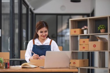 İnternet üzerinden nakliye alışverişi, iş yerindeki karton kutuya adres yazan küçük işletme sahibi gençler. Küçük işletme girişimcisi KME ya da ofiste kutuyla çalışan serbest çalışan Asyalı kadın..