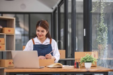 İnternet üzerinden nakliye alışverişi, iş yerindeki karton kutuya adres yazan küçük işletme sahibi gençler. Küçük işletme girişimcisi KME ya da ofiste kutuyla çalışan serbest çalışan Asyalı kadın..