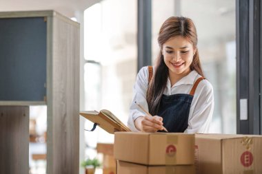 Startup small business entrepreneur SME, asian woman packing cloth in box. Portrait young Asian small business owner home office, online sell marketing delivery, SME e-commerce telemarketing concept