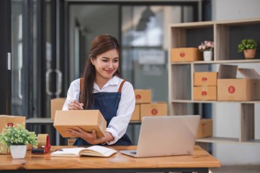 Portrait business woman smile and use tablet checking information on parcel shipping box before send to customer. Entrepreneur small business working at home. SME business online marketing...