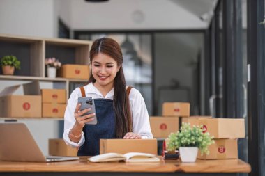 Girişim KOBİ küçük işletme girişimcisi serbest çalışan Asyalı kadın kutu gibi başarılı akıllı telefon kullanıyor
