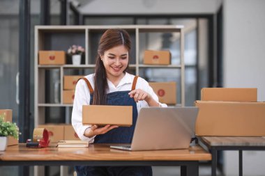Başlangıçta mutlu Asyalı kadın işyeri sahibi ev ofisinde gişe hasılatıyla çalışıyordu. Paket teslimat KOBİ tedarik zinciri, satın alma ve paket kutusunu müşterilere, Çevrimiçi KOBİ iş girişimcilerine teslim etmek üzere hazırlayın