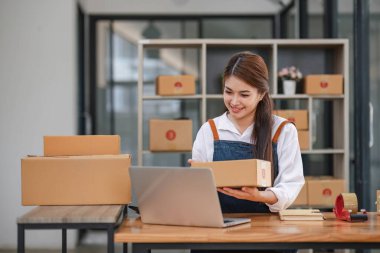Başlangıçta mutlu Asyalı kadın işyeri sahibi ev ofisinde gişe hasılatıyla çalışıyordu. Paket teslimat KOBİ tedarik zinciri, satın alma ve paket kutusunu müşterilere, Çevrimiçi KOBİ iş girişimcilerine teslim etmek üzere hazırlayın