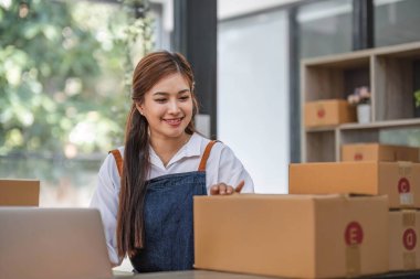 Başlangıçta mutlu Asyalı kadın işyeri sahibi ev ofisinde gişe hasılatıyla çalışıyordu. Paket teslimat KOBİ tedarik zinciri, satın alma ve paket kutusunu müşterilere, Çevrimiçi KOBİ iş girişimcilerine teslim etmek üzere hazırlayın