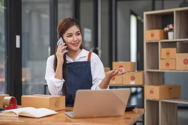 Startup SME small business entrepreneur of freelance Asian woman using a smartphone with box Cheerful success