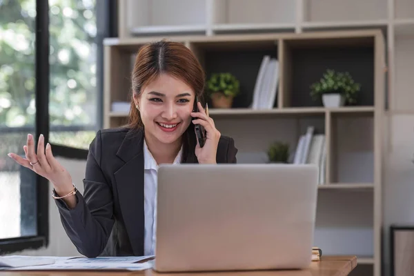 stock image Asian businesswoman in formal suit in office happy and cheerful during using smartphone and working..