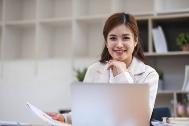 Asyalı iş kadını dizüstü bilgisayar kullanıyor ve ofiste hesap makinesi ile çalışıyor, mali raporu, iş planı yatırımını, mali analiz konseptini analiz etmeyi planlıyor....