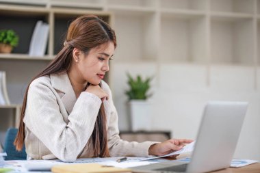 Asyalı ciddi bir iş kadınının portresi çalışma alanlarında dizüstü bilgisayara odaklanıyor ve düşünüyor. Grafik montaj için siyah ekran laptop. Kadın dizüstü bilgisayar çalışma konsepti..
