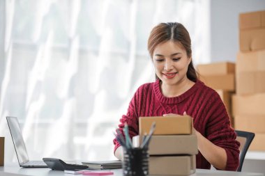 Çevrimiçi pazarlama paketi ögelerinin neşeli başarısı ile bilgisayar laptopu kullanarak gülümseyen bağımsız Asyalı kadının küçük işletme girişimciliğini başlatan