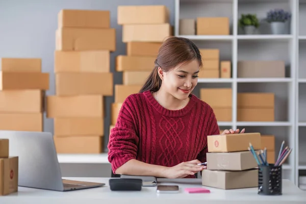 stock image Starting small business entrepreneur of independent Asian woman smiling using computer laptop with cheerful success of online marketing package box items
