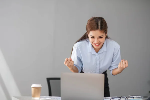 stock image Asian businesswomen show joyful expression of success at work smiling happily with a laptop computer in a modern office...