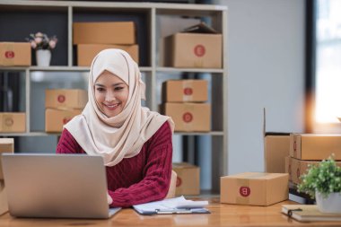 Müslüman Kadın çevrimiçi küçük işletme sahibi girişimci paketleme paketleme posta kutusu teslimat paketi masanın üzerinde. Ticarette sevkiyat hizmeti konsepti düştü...