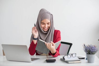 Güzel Müslüman iş kadını portresi. Kameraya gülümsüyor, masasında oturuyor....
