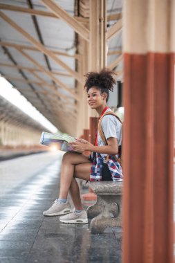 Sırt çantalı genç bayan gülen gezgin tren istasyonunda tren beklerken haritasını arıyor. Yüksek kalite fotoğraf..