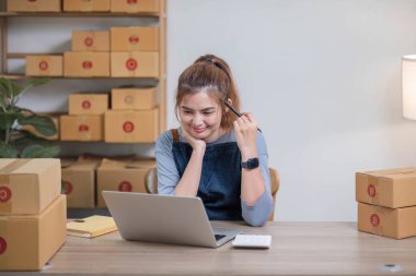 Küçük işletme girişimcisi KME, kutuda kumaş paketleyen Asyalı kadın. Portre genç Asyalı küçük işletme sahibi ev sahibi, çevrimiçi satış pazarlama teslimatı, KME e-ticaret tele pazarlama kavramı