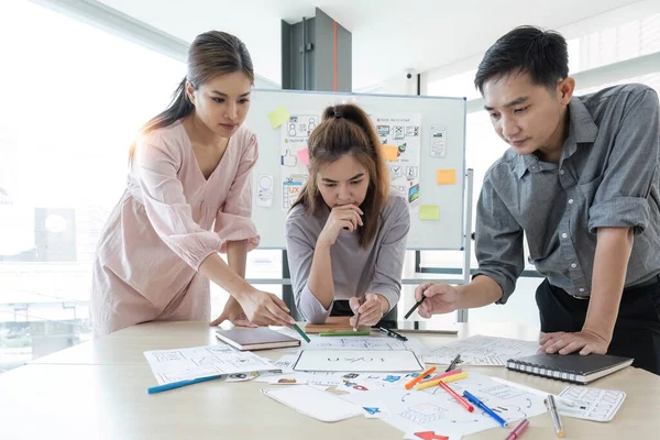 stock image group of asian ux developer and ui designer serious brainstorming about mobile app interface on meeting at modern office.Creative digital development agency.