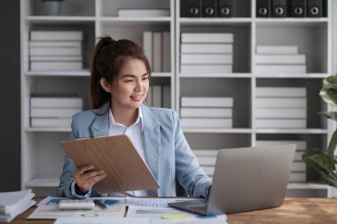 Ofiste dizüstü bilgisayarda çalışan neşeli iş kadını, iş yerinde resmi takım elbiseli Asyalı mutlu iş kadını. Çekici bayan ofis çalışanı gülümsemesi.