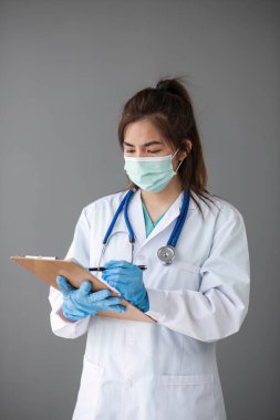 Kendine güvenen, profesyonel bir kadın doktor ya da hemşire bir hastane danışma odasında masa başında dizüstü bilgisayarla çalışıyor..