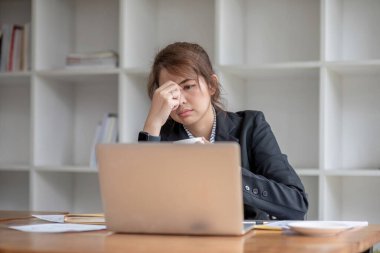 Asyalı kadın ofis çalışanı dizüstü bilgisayarına bakarken stresli ve üzgün..