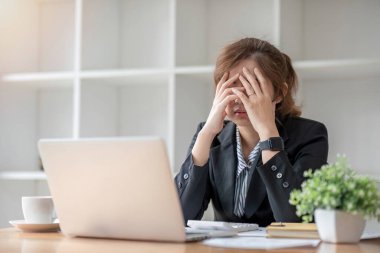 Asyalı kadın ofis çalışanı dizüstü bilgisayarına bakarken stresli ve üzgün..