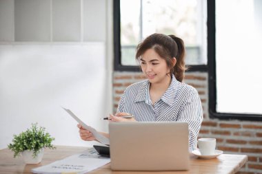 Bir ofis masasında, vergi, rapor, muhasebe, istatistik ve analitik araştırma konseptinde matematik finansmanı için dizüstü bilgisayar kullanan Asyalı İş kadını.