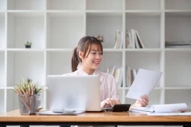 Asyalı iş kadını dizüstü bilgisayar kullanıyor ve çalışıyor. Muhasebe analizi yapan iş kadını yatırım verilerini rapor ediyor..