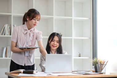 İki genç Asyalı iş kadını yeni başlatılan proje fikir sunumuyla görüştü, ofiste istatistik ve yatırım pazarını analiz etti.