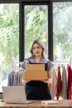 Çevrimiçi iş konsepti, Asyalı iş kadınları müşterilerine teslimat için paket kutu ürün bulunduruyorlar.