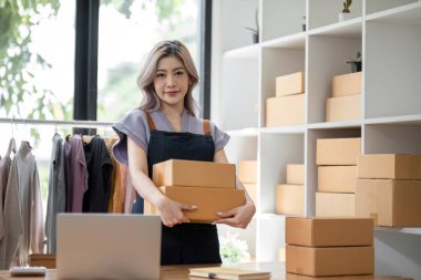 Çevrimiçi iş konsepti, Asyalı iş kadınları müşterilerine teslimat için paket kutu ürün bulunduruyorlar.