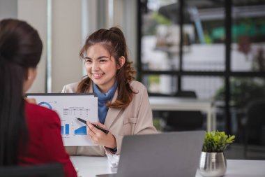 İki iş kadını grafikler ve finans verileri hakkında tartışıyor ve bilgi alışverişinde bulunuyor..