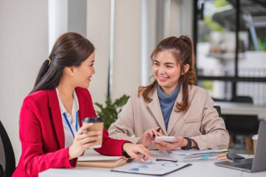 İki iş kadını grafikler ve finans verileri hakkında tartışıyor ve bilgi alışverişinde bulunuyor..