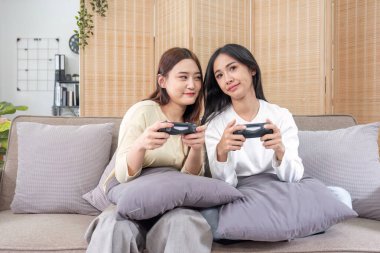 Genç Asyalı çift evde video oyunu oynuyor oturma odasında eğleniyorlar...