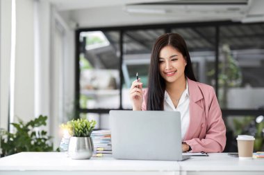 İş kadını, sabahları ofiste bir fincan kahve içerken dizüstü bilgisayarla çalışıyor...