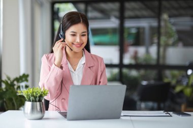 Bir çağrı merkezi operatörü iş detaylarını dizüstü bilgisayardaki bir müşteriye açıklar...