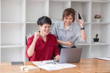 İki neşeli Asyalı iş adamı, son zamanlarda bitirdikleri işleri mutlu yüzleriyle dizüstü bilgisayarlarında izliyorlar...