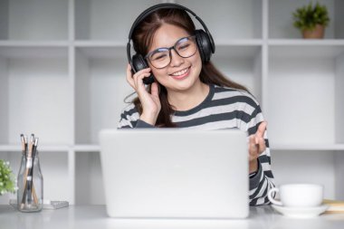 Oturma odasında dizüstü bilgisayarla internet üzerinden mutlu bir şekilde çalışan genç kız öğrenci...